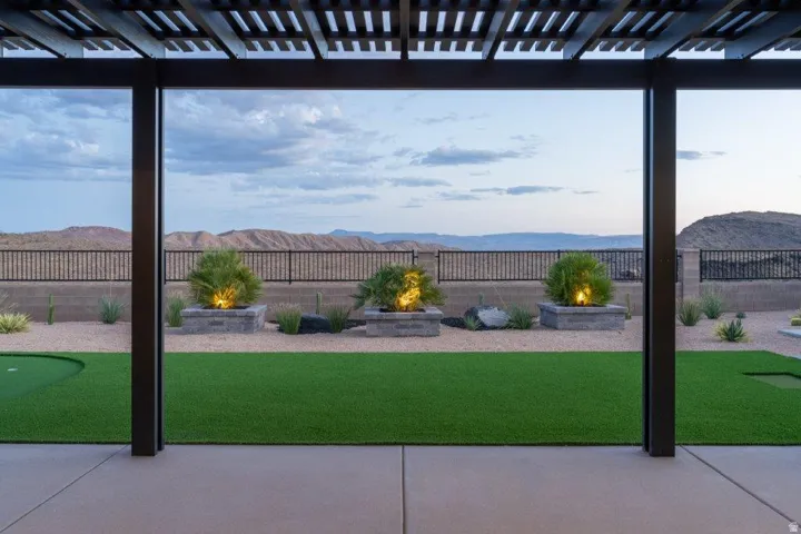 Expansive backyard with manicured lawn, mature landscaping including ornamental grasses and flowering shrubs, and panoramic vistas of mountains and distant terrain