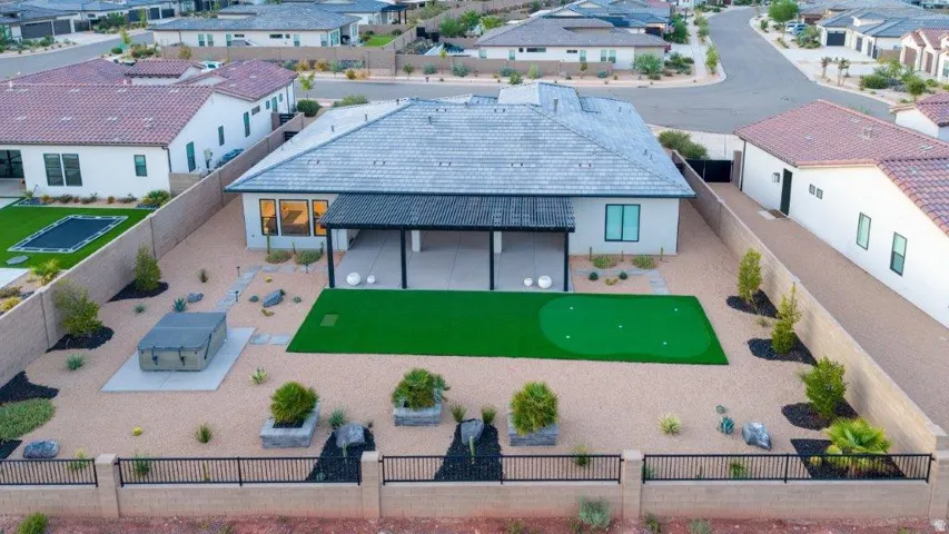 Spacious backyard featuring a putting green, a covered patio, a hot tub, and xeriscaping