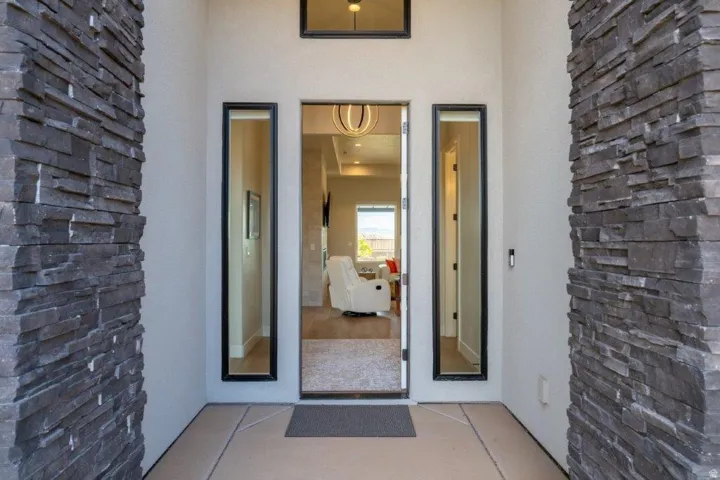 Stacked stone accent walls frame the entry, featuring a modern transom window and two full-length sidelight windows