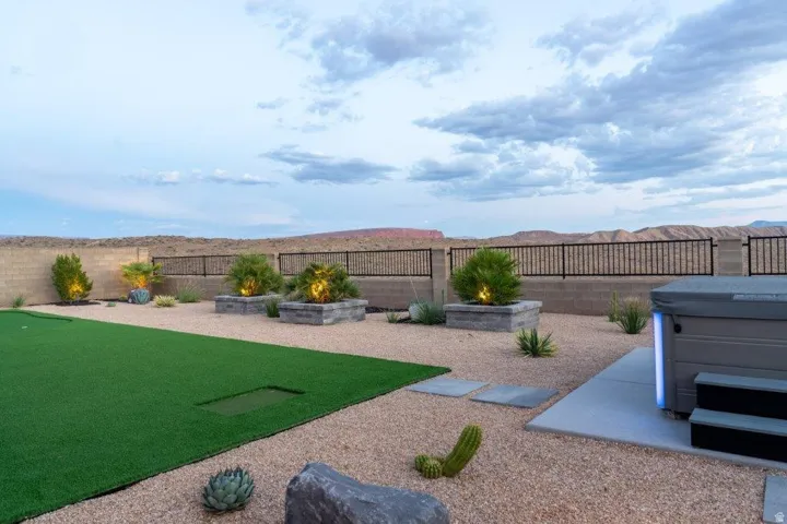 Expansive backyard featuring artificial turf putting green, gravel landscaping, and a built-in hot tub