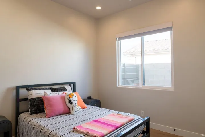Recessed ceiling lighting, a large window with roller shades, and light-toned walls