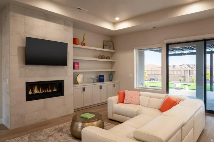 Integrated fireplace with tile surround, built-in shelving, large window, sliding glass door, and recessed lighting