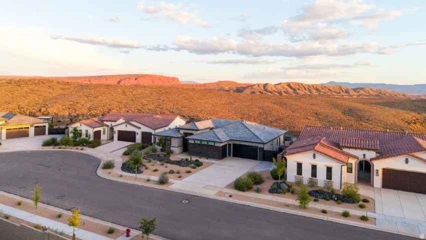 Modern stucco exterior with a tile roof, desert landscaping, and a three-car garage