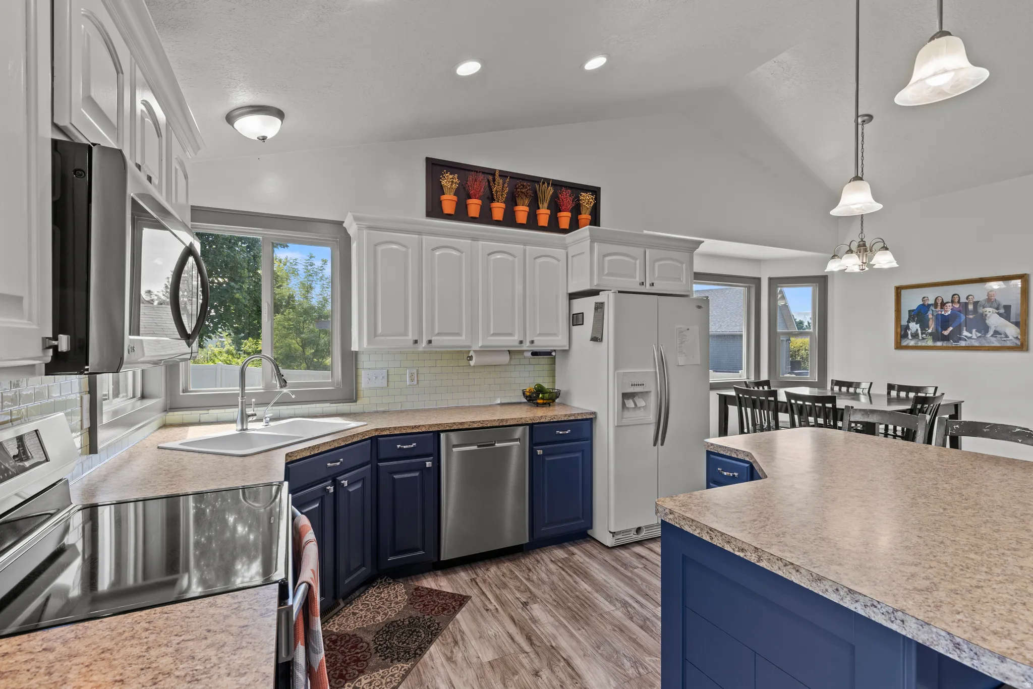Chef's kitchen showcasing custom cabinetry in navy and white finishes, stainless steel appliances including a side-by-side refrigerator, and pendant lighting