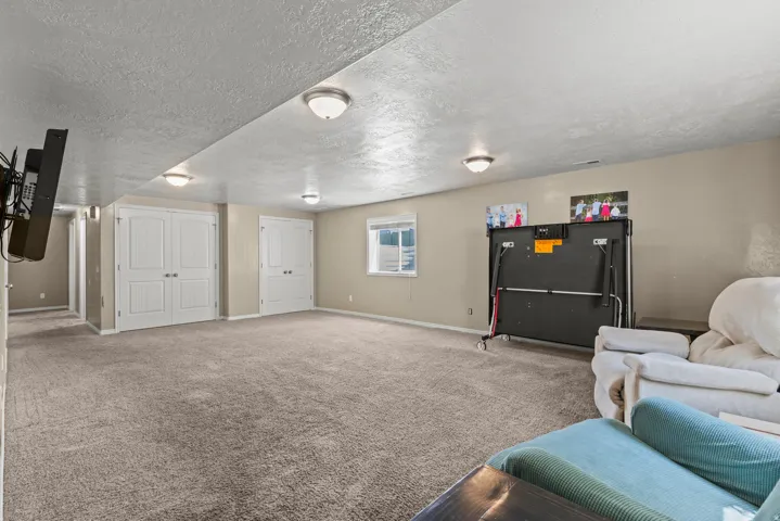 Spacious recreation room featuring recessed ceiling lighting, neutral carpeting throughout, and multiple closet storage options