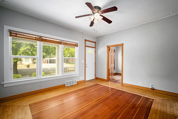 Hardwood flooring, white trim, wood door frames, ceiling fan, and large windows