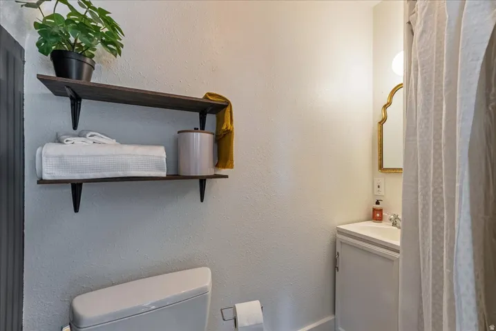 Wall-mounted shelving, corner vanity with a built-in sink, and a decorative framed mirror