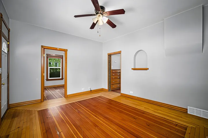 Hardwood flooring, ceiling fan, architectural wall niche with wood shelf, and wood trim throughout
