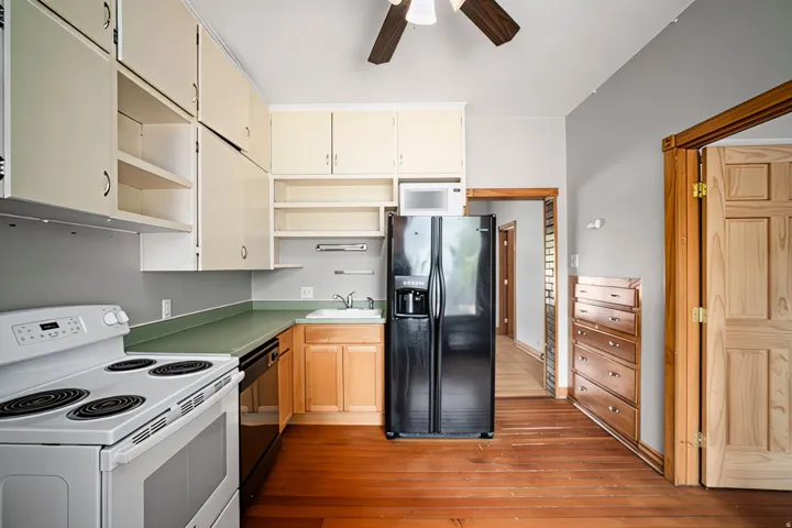 Kitchen featuring warm wood-finish flooring, light-toned cabinetry, and a ceiling fan
