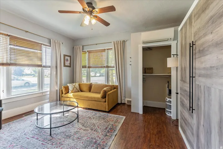 Wood-finish flooring, ceiling fan, and multiple windows with blinds