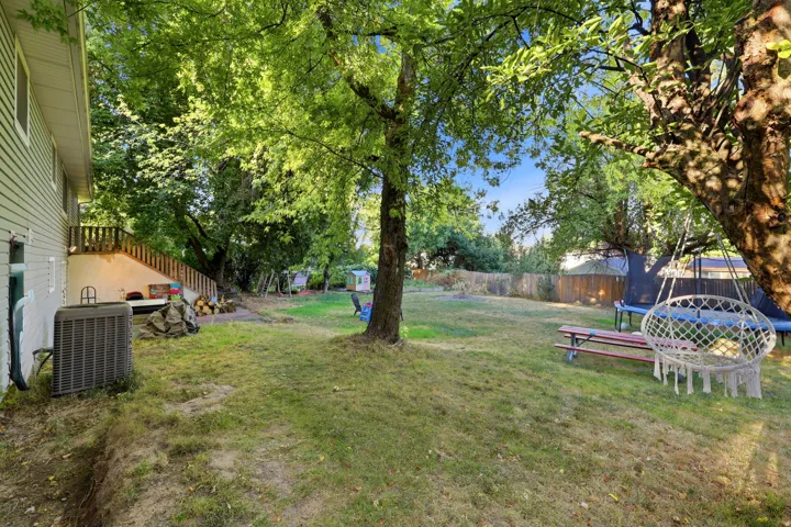 Expansive backyard featuring mature trees, a ground-level patio, and wood fencing