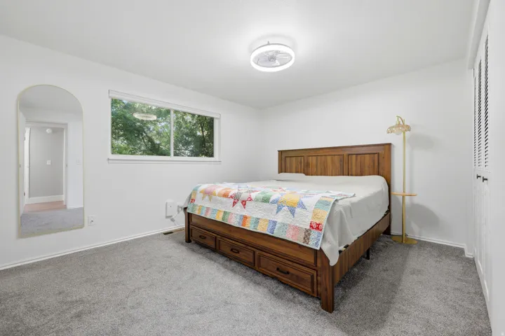 White walls, gray carpeting, and a window with a green outdoor backdrop