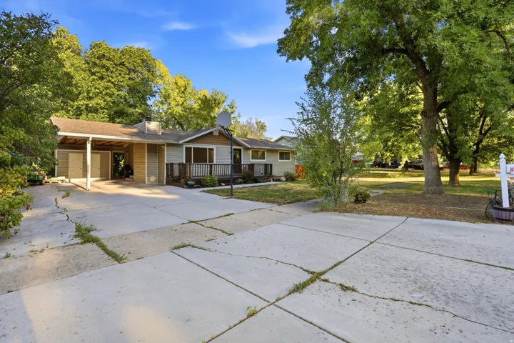 Single-story residence with a covered carport, front porch with wood railing, and a paved driveway
