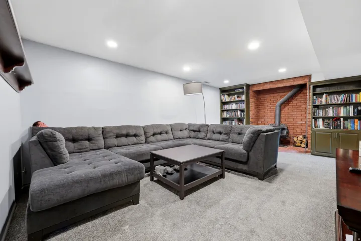 Recessed lighting illuminating a brick-faced wood-burning stove with a metal flue