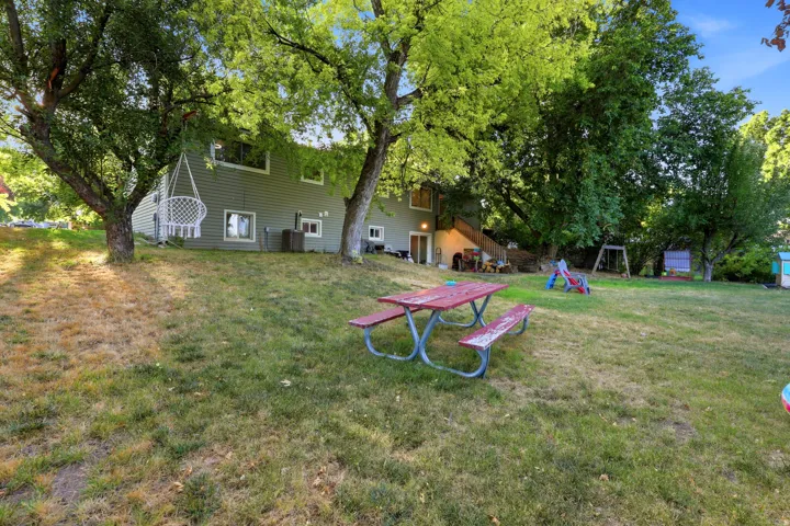 Expansive backyard featuring mature trees and a sloped lawn