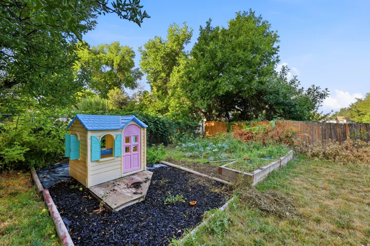 Backyard featuring a wooden privacy fence, mature trees, and a raised garden bed