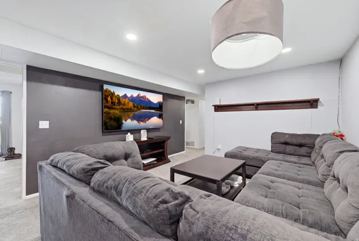 Recessed ceiling lighting, a dark accent wall, and a built-in wood shelf