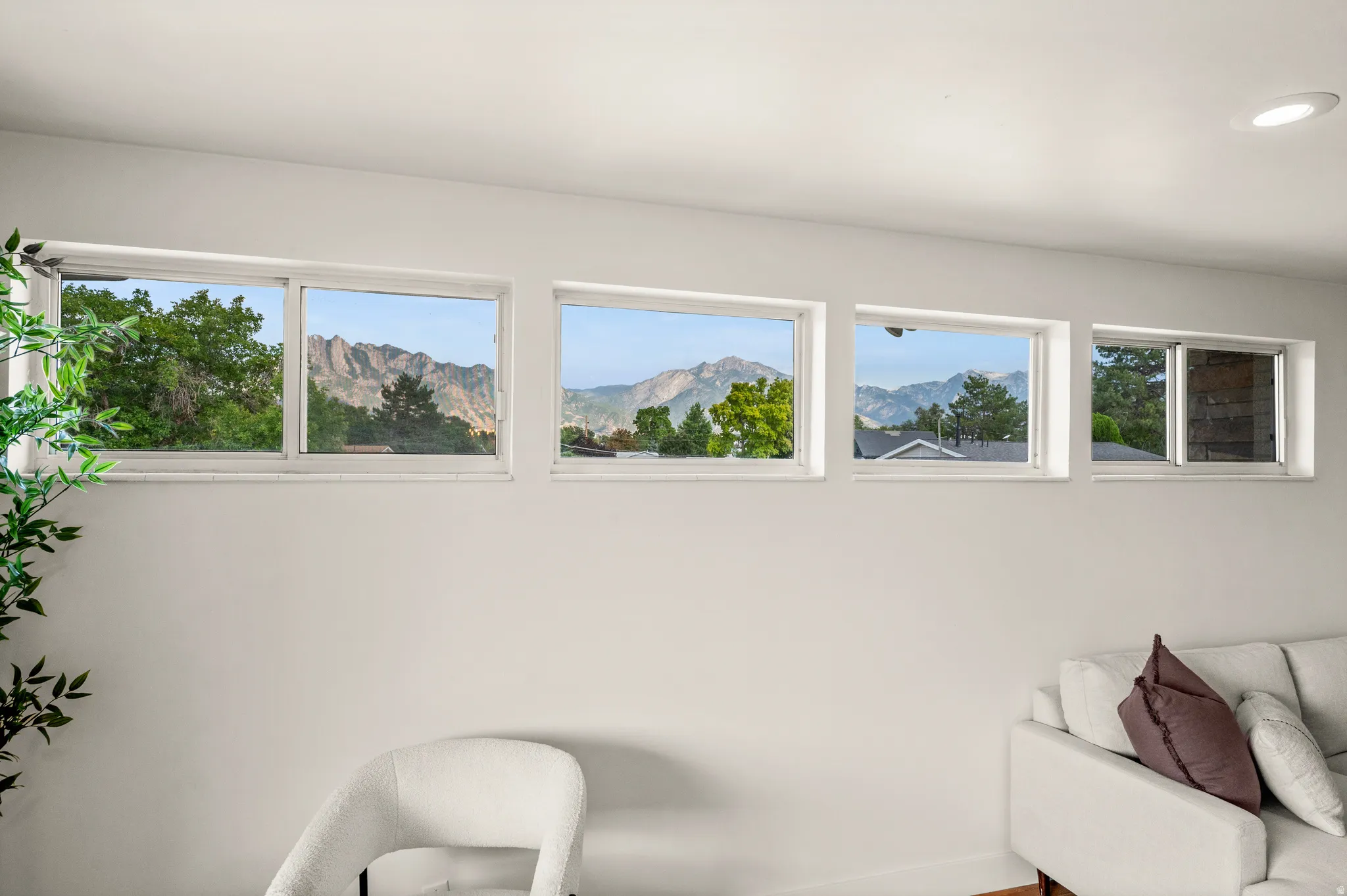 Bright upper-level room flooded with natural light through a continuous band of six transom windows showcasing mountain vistas