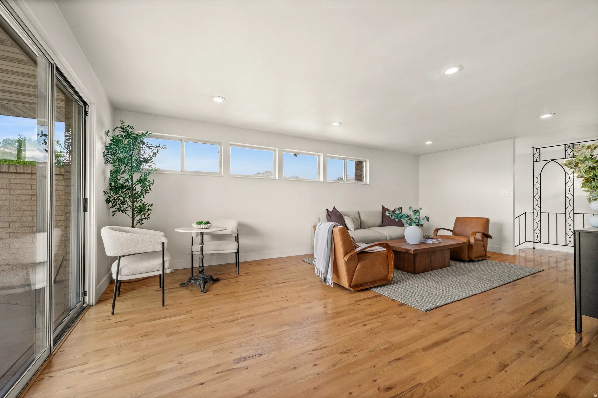 Bright, open living space featuring hardwood flooring throughout, abundant natural light from expansive transom windows, and recessed ceiling lighting