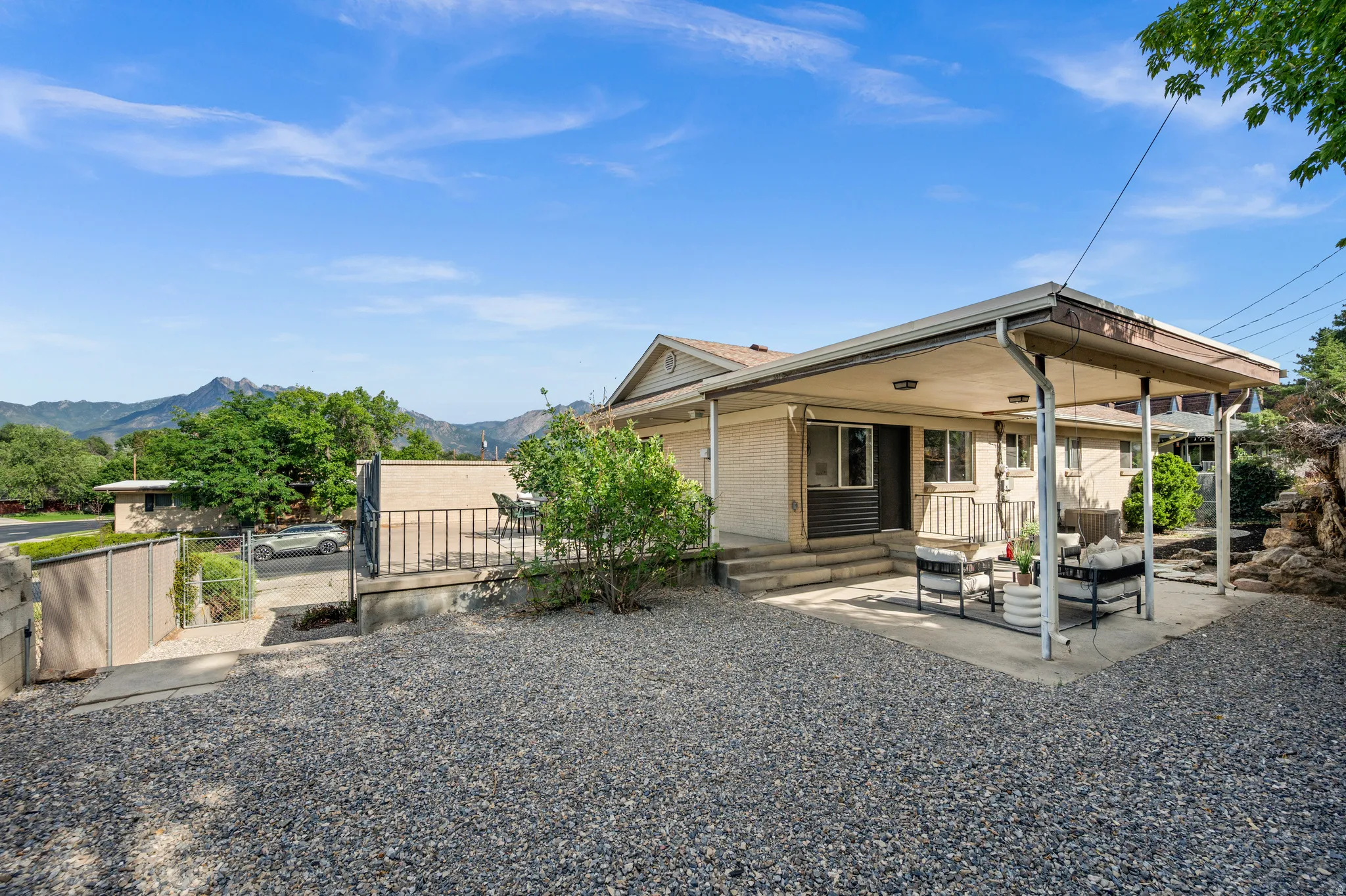 Spacious gravel courtyard with mature landscaping and mountain backdrop