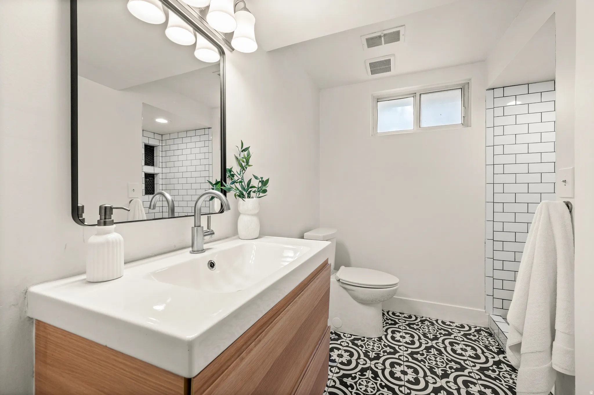 Modern bathroom featuring a floating wood-finish vanity with an integrated rectangular sink, polished chrome faucet, and white quartz countertop