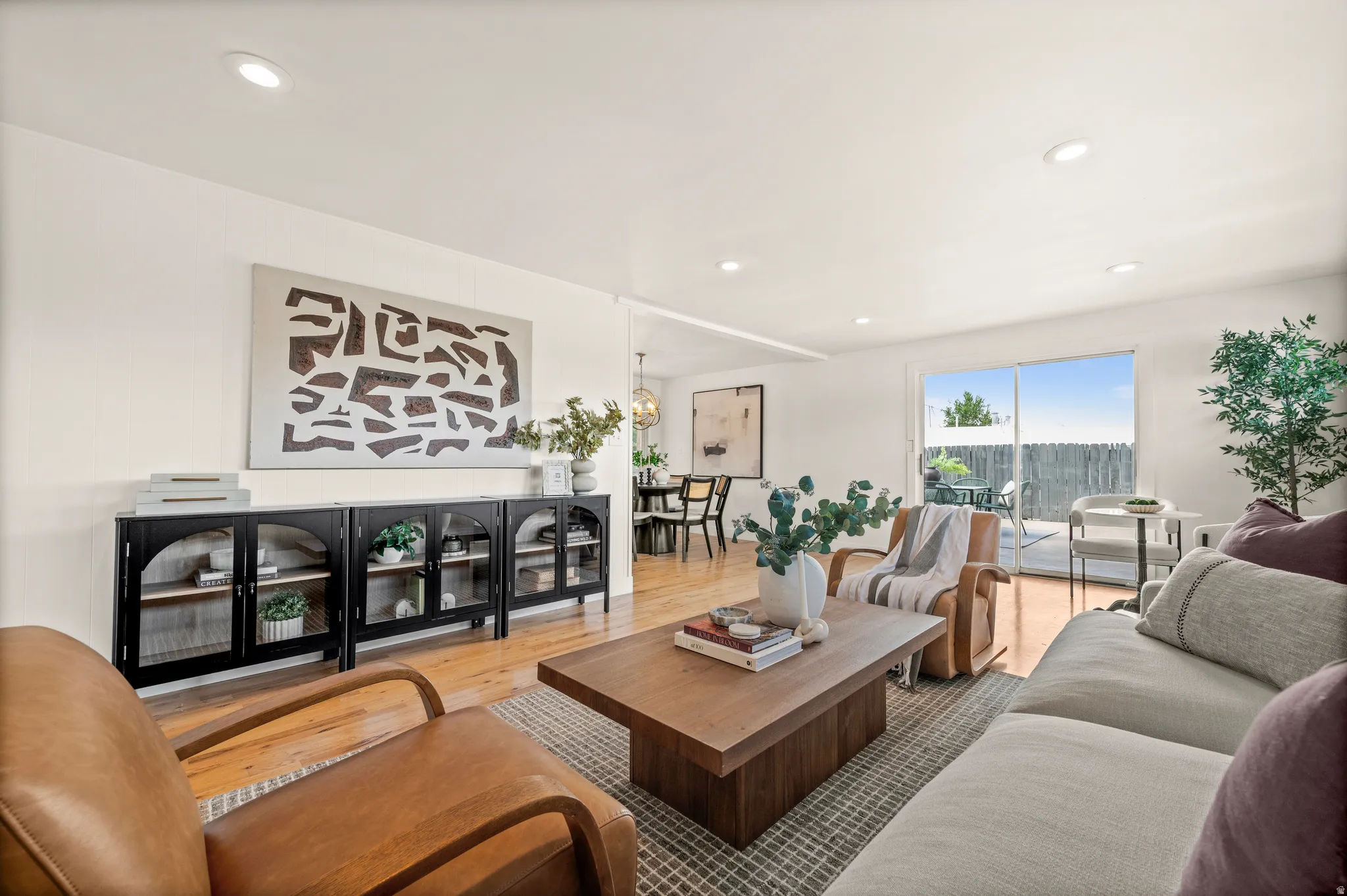 Sophisticated living room featuring a wood-finish floor, recessed ceiling lighting, and expansive windows with natural light