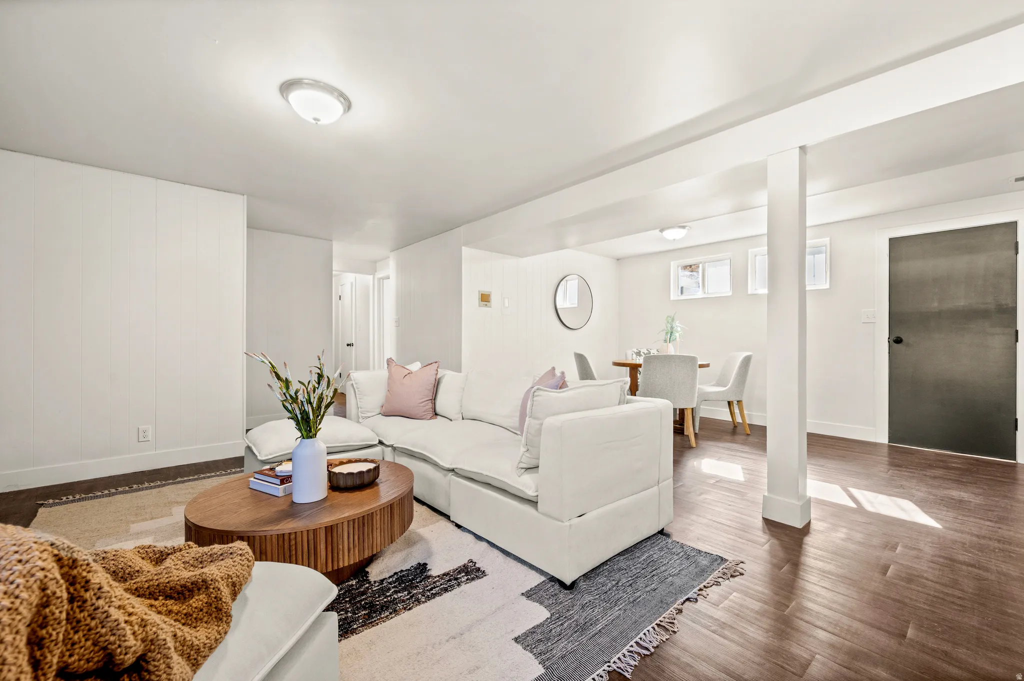 Bright, open-concept basement featuring hardwood flooring throughout, multiple support columns, and recessed ceiling lighting