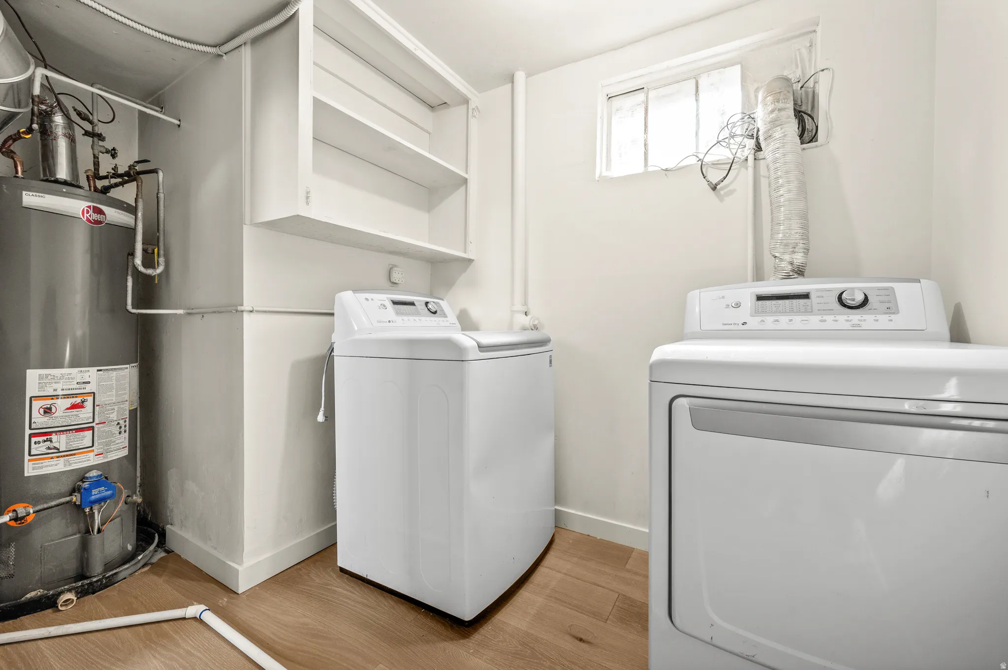 Laundry area featuring a water heater, built-in shelving, wood-finish flooring, and a window