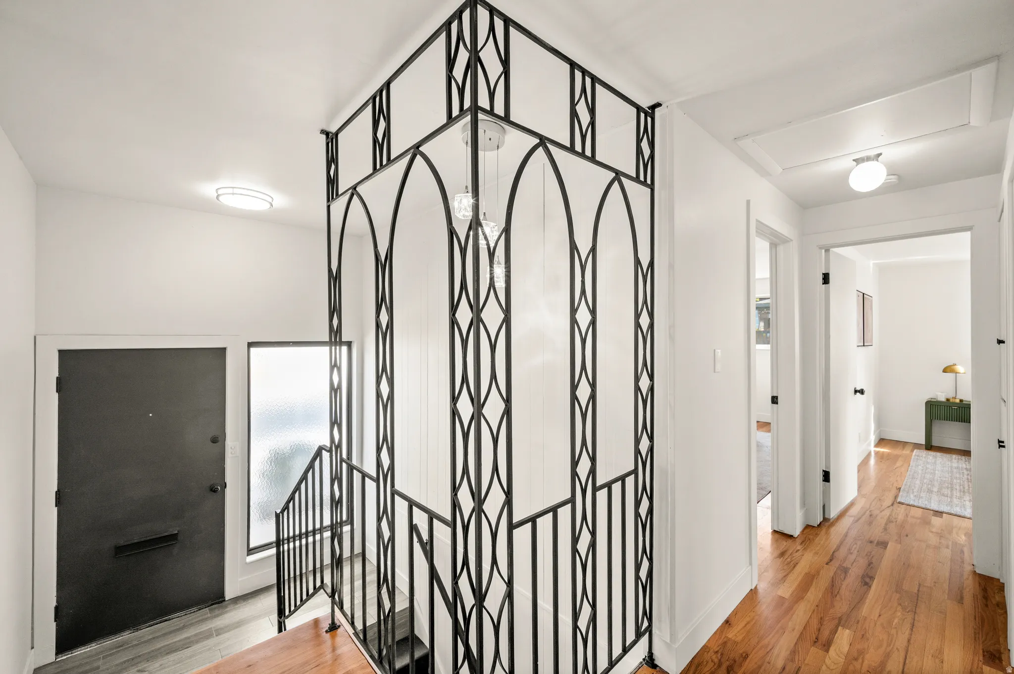 Elegant foyer featuring soaring ceilings, ornate wrought-iron architectural detailing, and warm wood-finish flooring throughout
