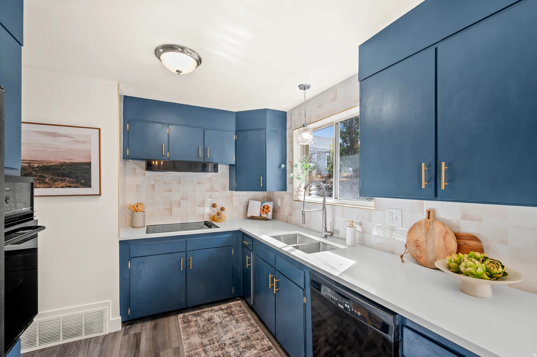 Modern kitchen featuring deep blue cabinetry with brushed gold hardware, white subway tile backsplash, and white quartz countertops