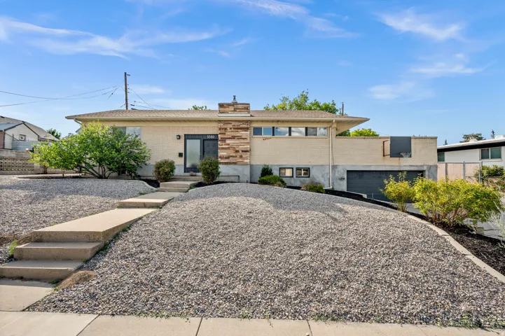 Modern residence featuring a geometric stone-finished entry courtyard with integrated concrete stepping stones, complemented by mature landscaping and native plantings