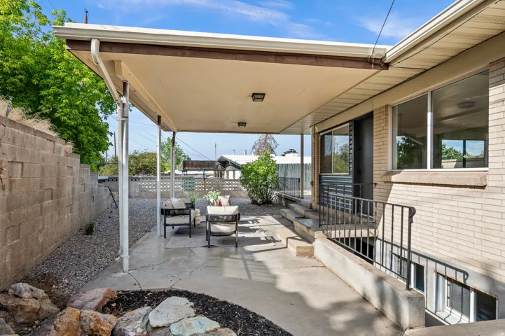 Covered patio with concrete flooring and overhead shade structure, featuring metal railings and direct access to the home's exterior