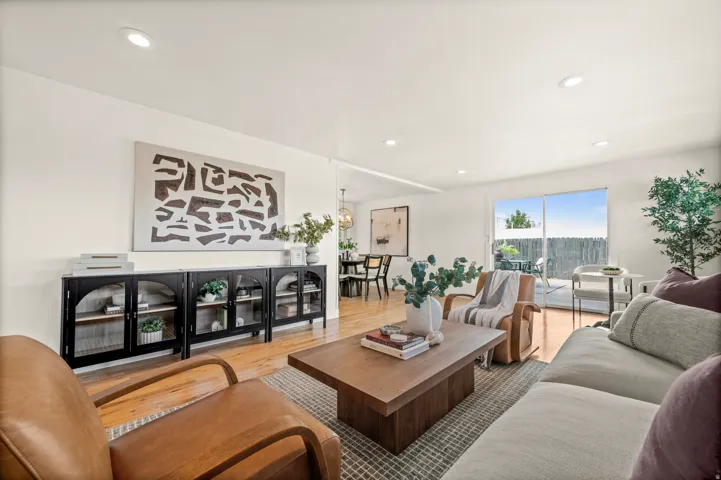 Sophisticated living room featuring a wood-finish floor, recessed ceiling lighting, and expansive windows with natural light