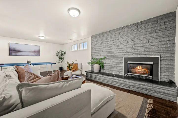 Stone accent wall with a built-in fireplace, dark wood-finish flooring, and multiple window openings