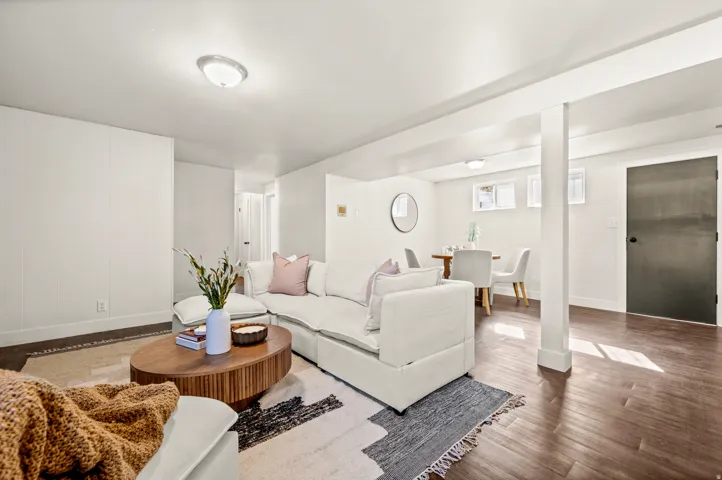 Bright, open-concept basement featuring hardwood flooring throughout, multiple support columns, and recessed ceiling lighting