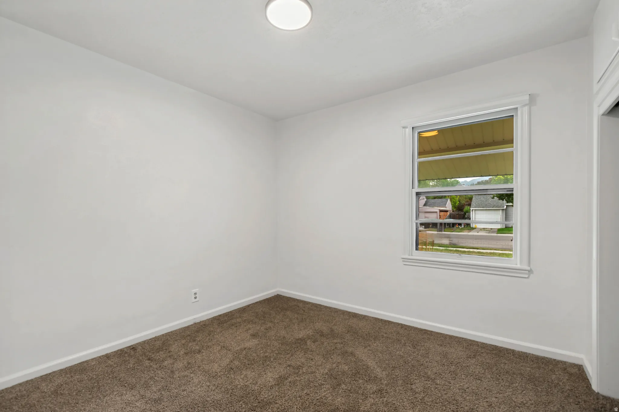 Neutral bedroom featuring plush carpeting, recessed ceiling lighting, and a large operable window with integrated storage shelving
