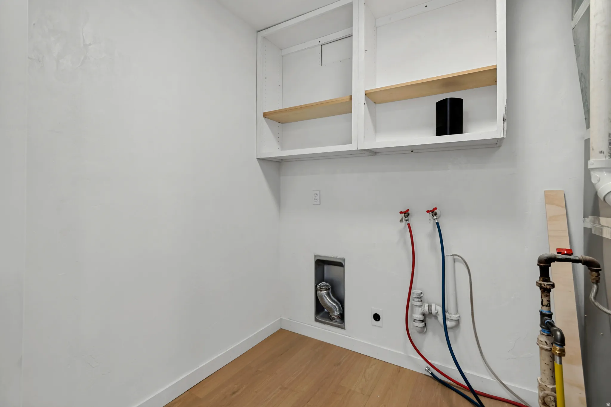 Utility room featuring white cabinetry with wood-finish shelving, wood-finish flooring, and pre-installed electrical infrastructure with visible wiring connections