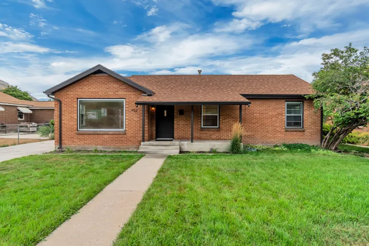 Brick exterior featuring a covered entry, pitched roof, and a concrete walkway
