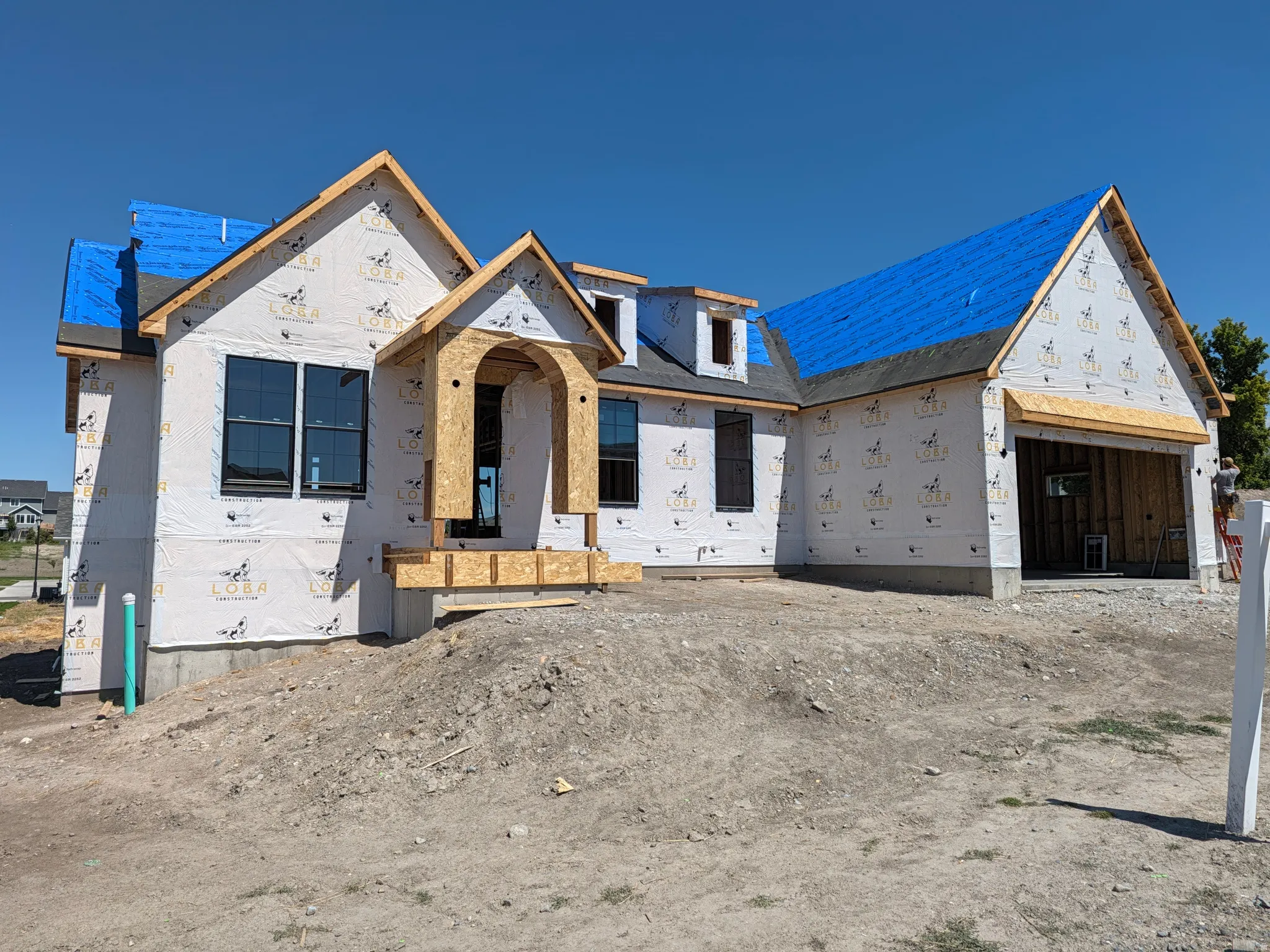 New construction home featuring a prominent arched entry, multiple gables, and an attached garage