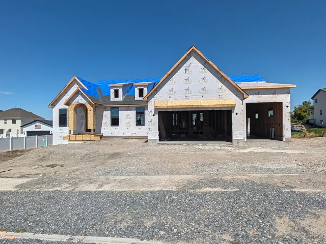 New construction residence featuring a two-car garage, an additional single-car garage, and multiple dormer windows