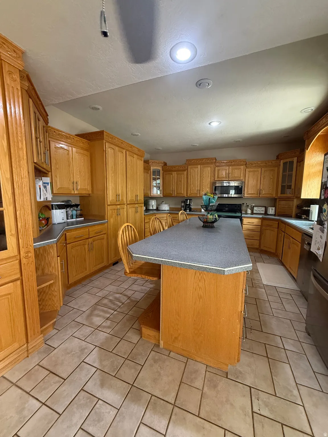 Kitchen featuring extensive wood cabinetry, a large central island with a countertop, recessed lighting, and tile flooring