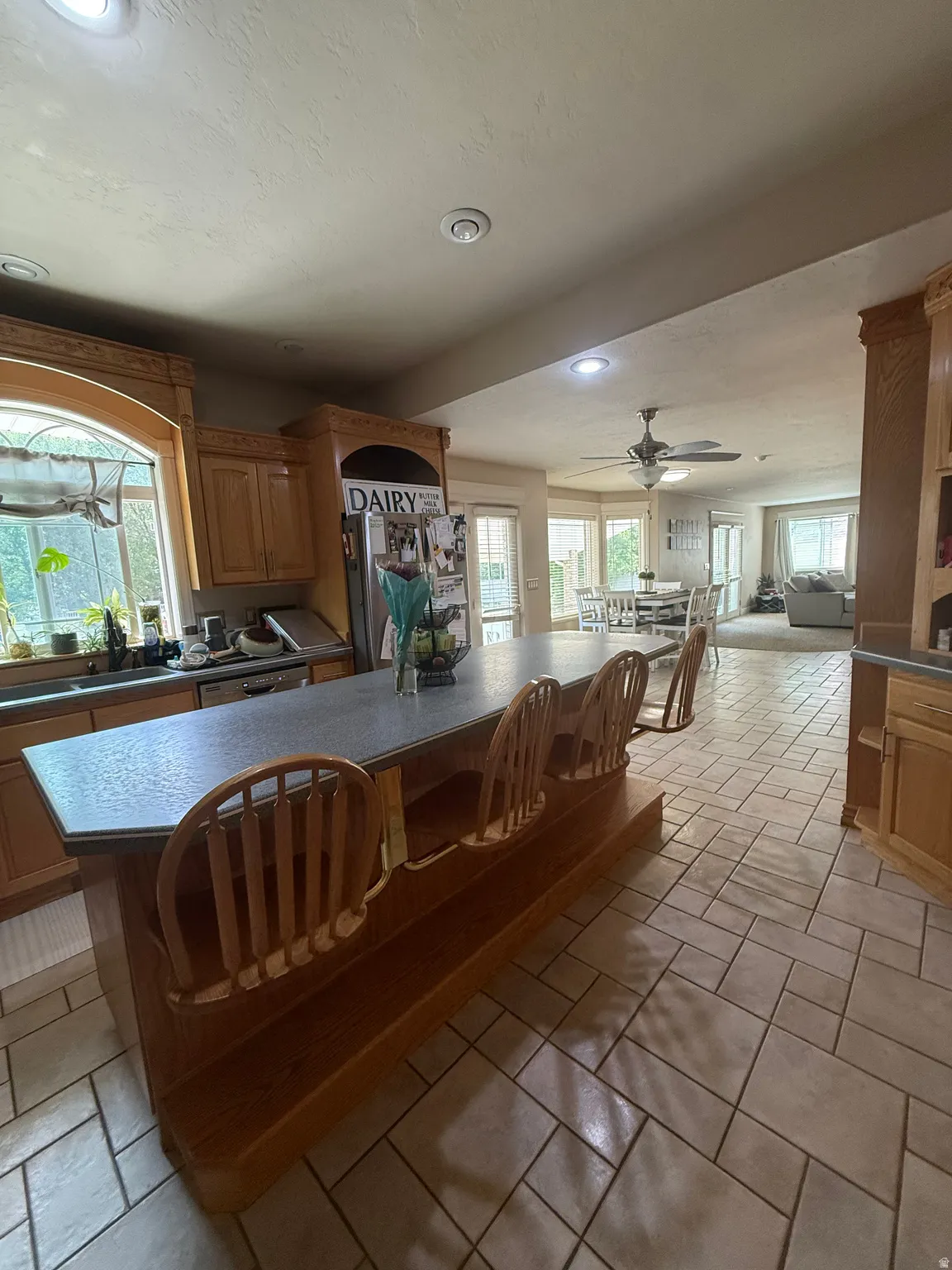 Kitchen featuring wood cabinetry, an extended island with a dark countertop, recessed lighting, and tile flooring