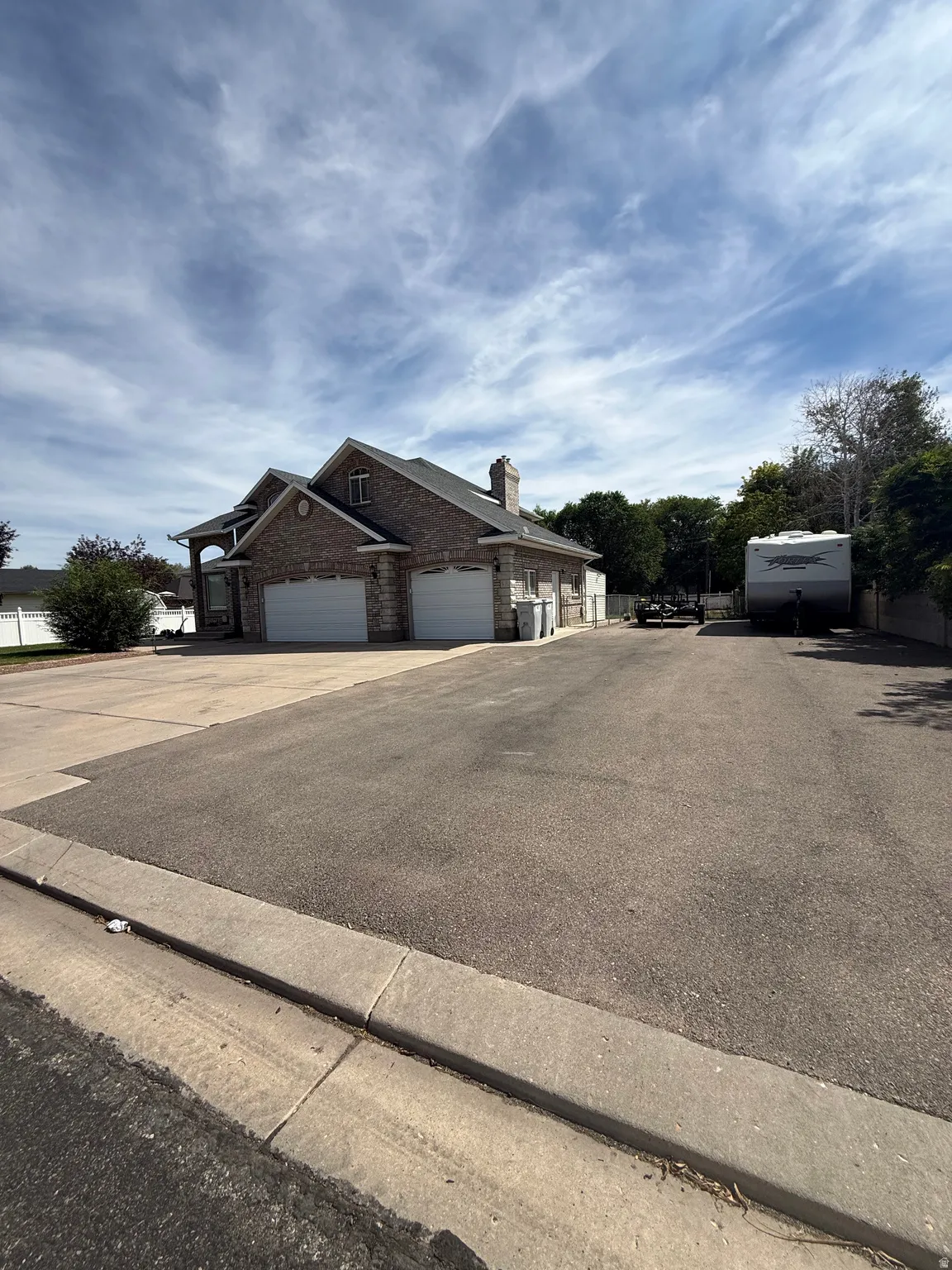 Spacious driveway with expansive asphalt parking area and mature landscaping