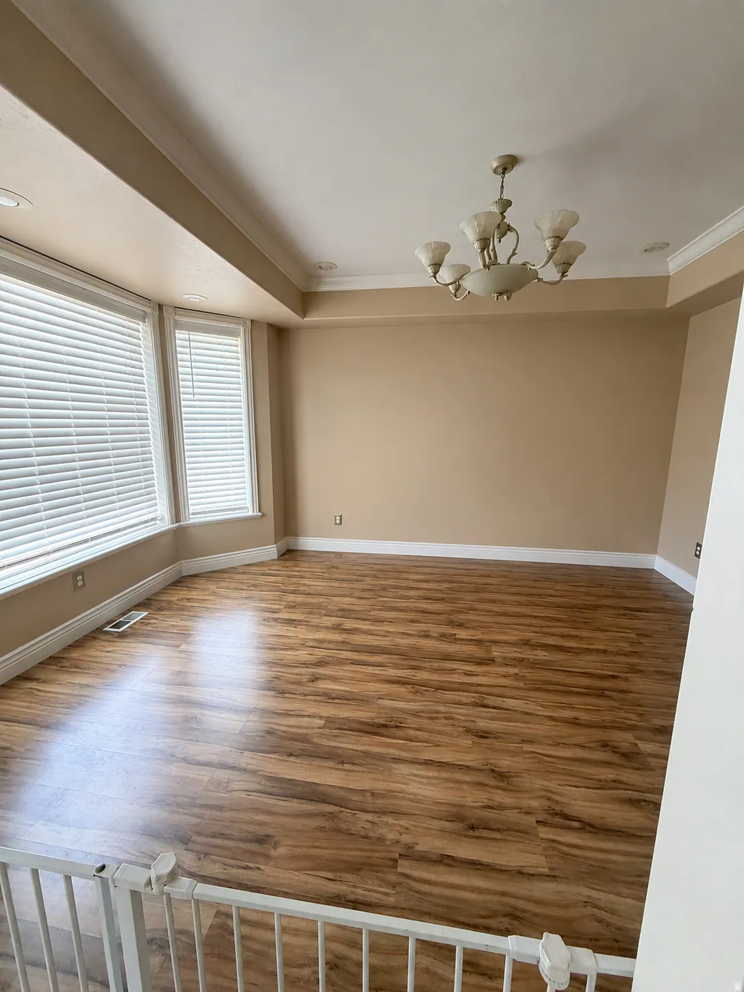 Wood-finish flooring, bay window with blinds, recessed lighting, and a decorative ceiling fixture