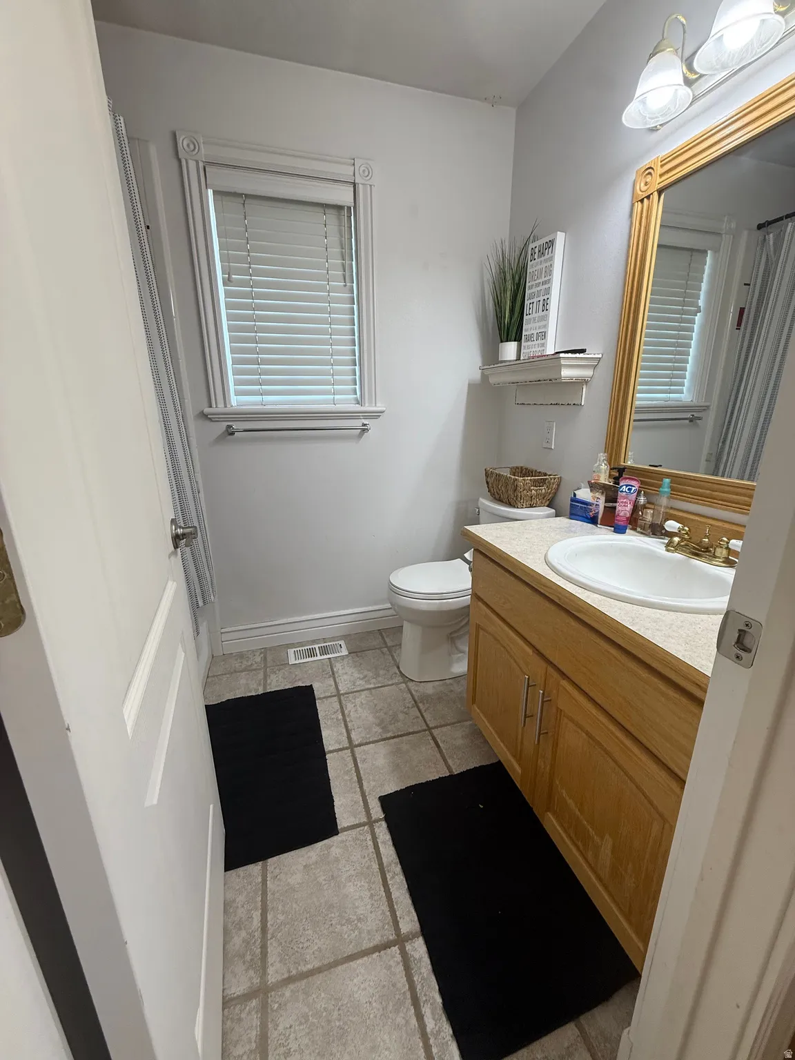 Tile flooring with a single vanity featuring a built-in sink and wood-finish cabinetry