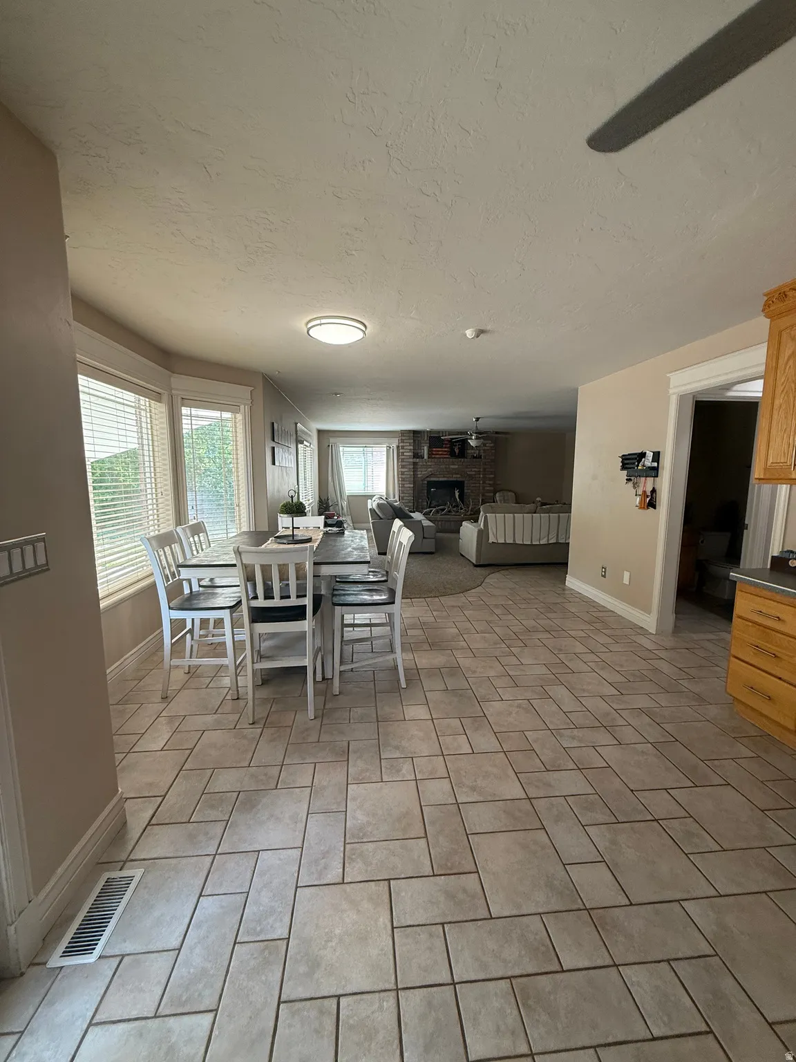 Open-concept kitchen and dining area featuring tile flooring in a herringbone pattern, recessed ceiling lighting, and large windows with natural light