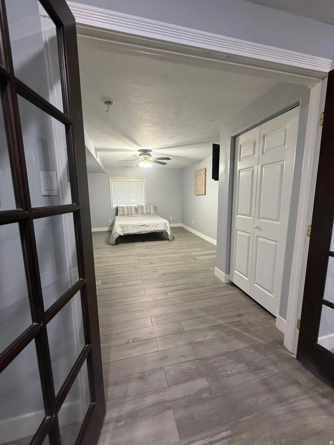 Spacious primary hallway with wood-finish flooring, ceiling fan, and access to multiple rooms