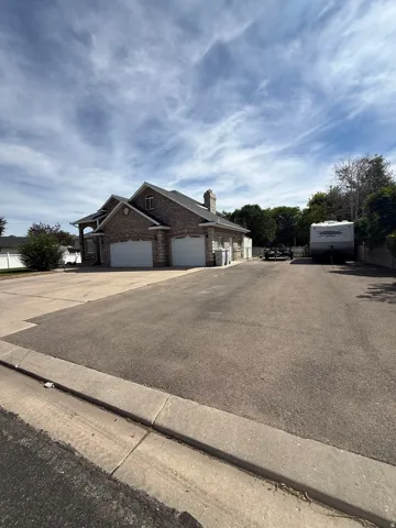 Spacious driveway with expansive asphalt parking area and mature landscaping