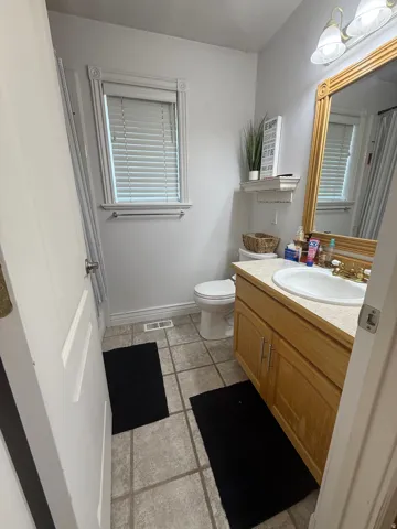 Tile flooring with a single vanity featuring a built-in sink and wood-finish cabinetry