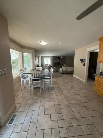 Open-concept kitchen and dining area featuring tile flooring in a herringbone pattern, recessed ceiling lighting, and large windows with natural light